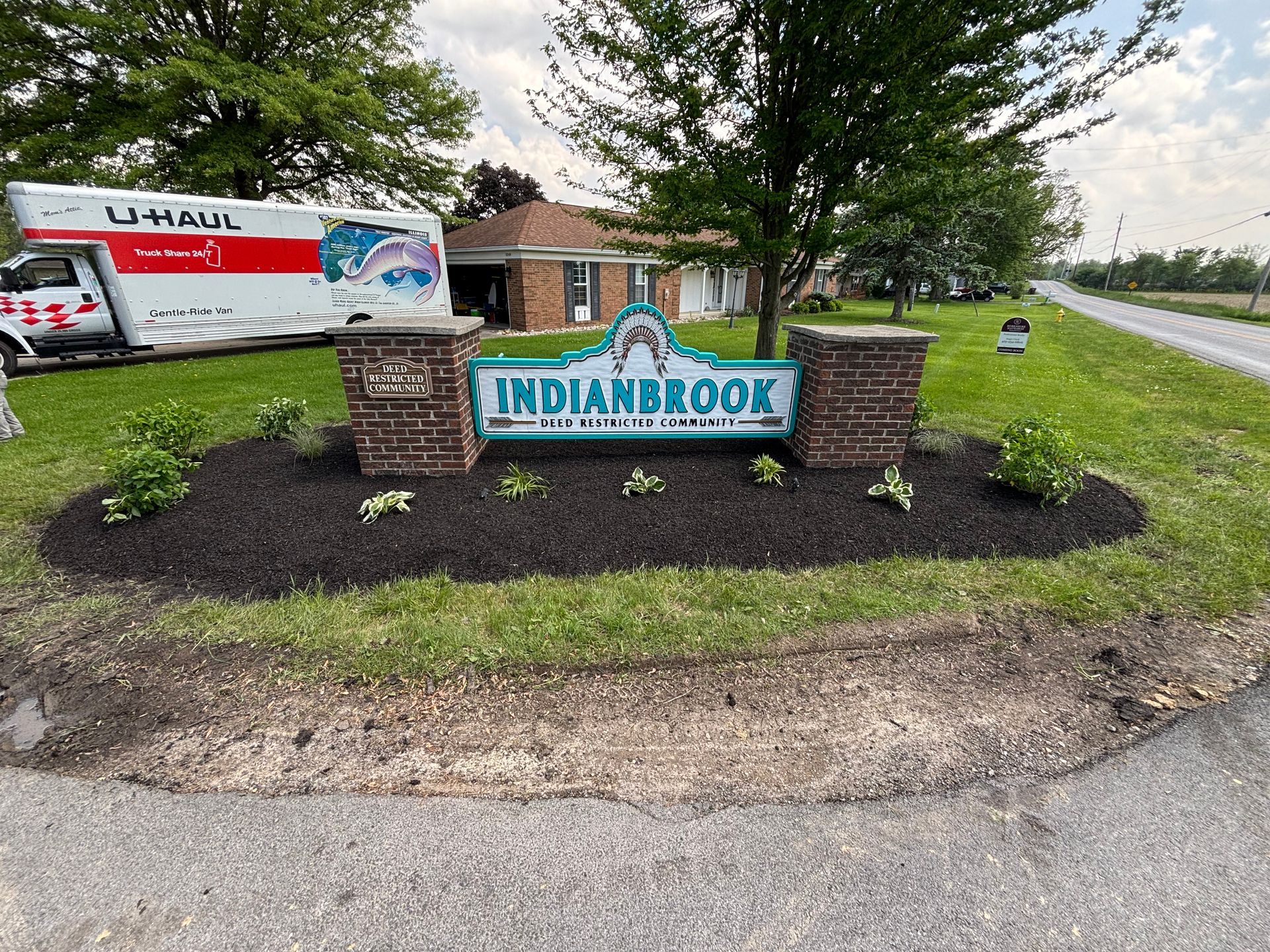 Indianbrook neighborhood sign with a U-Haul truck, a one-story house, and fresh landscaping.