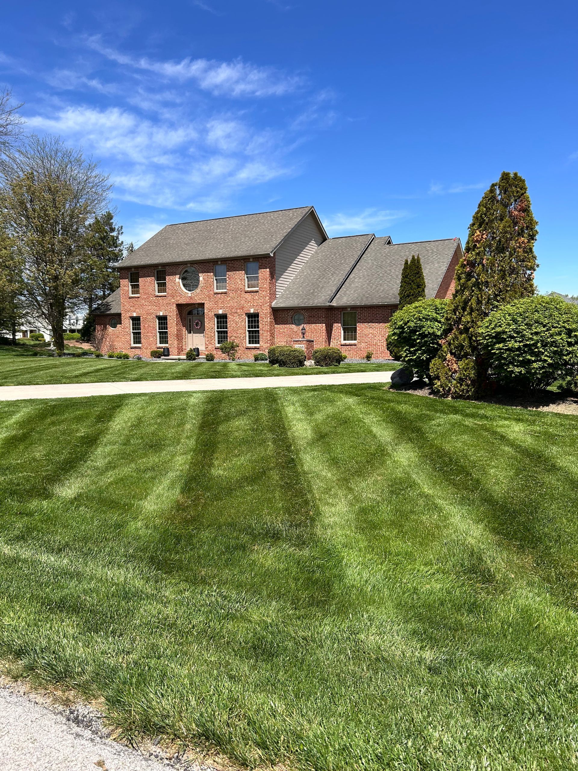 Brick house with well-manicured lawn, blue sky.