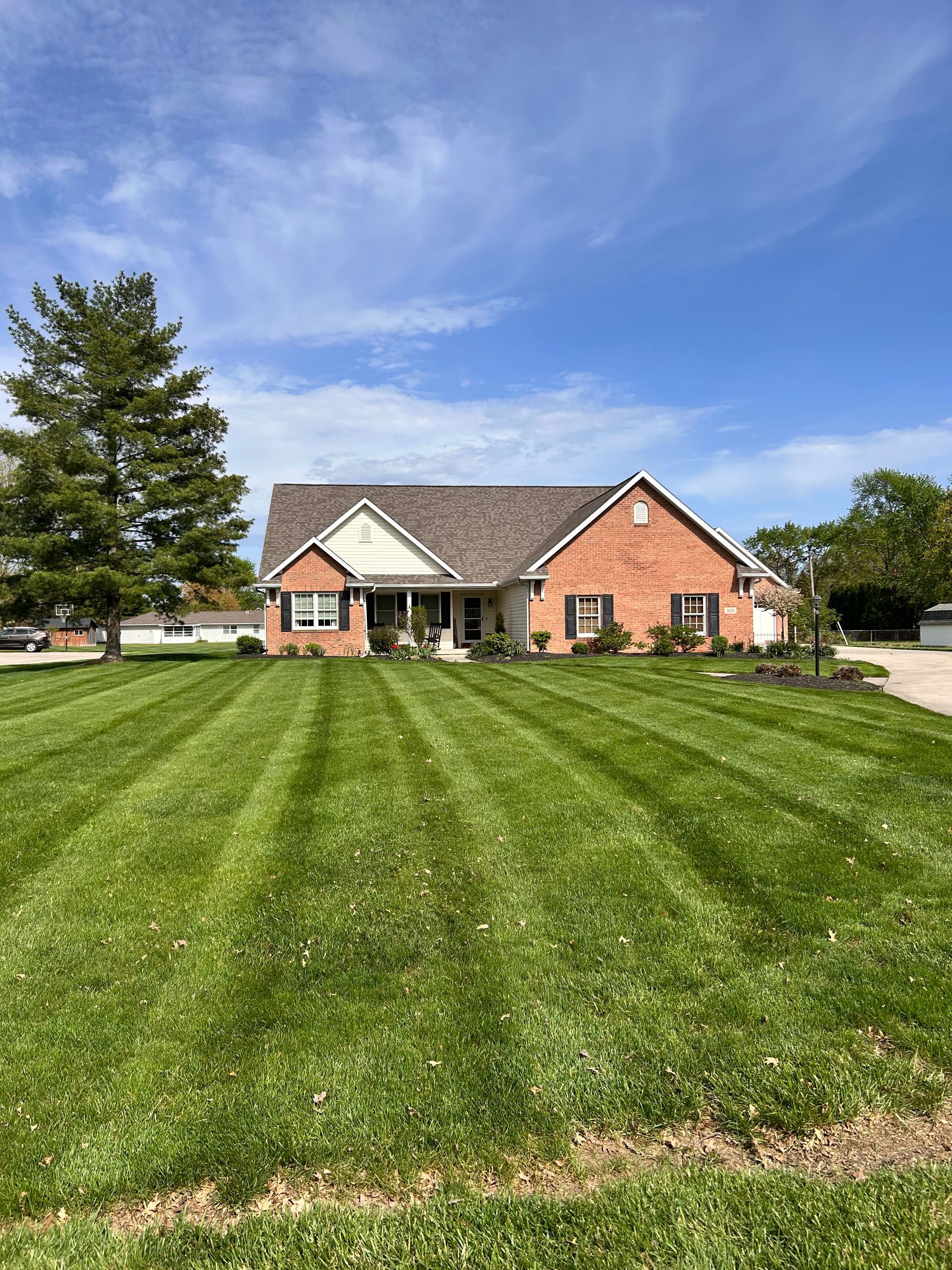 Brick house with a neatly striped green lawn under a blue sky.
