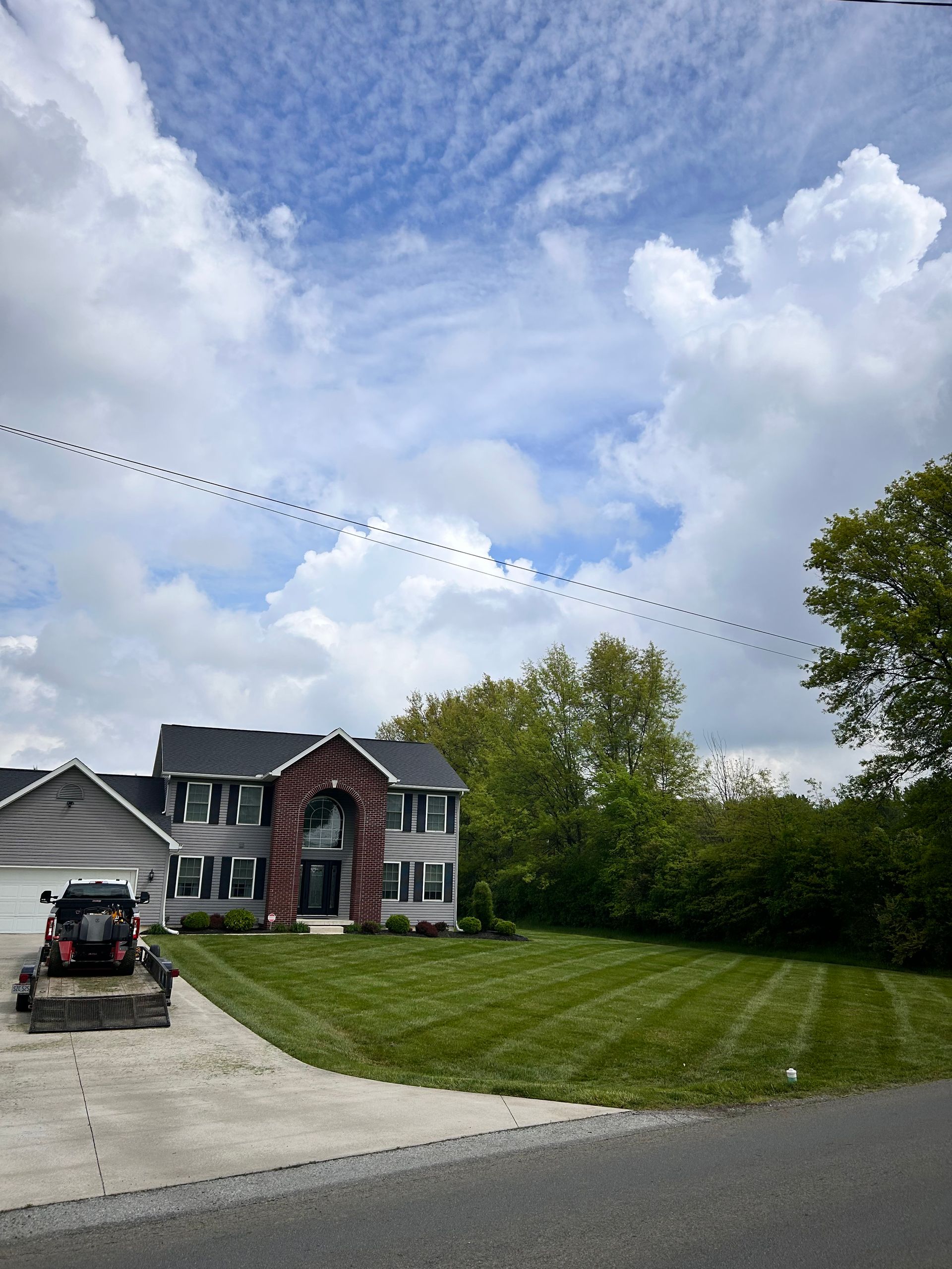 Two-story house with a green lawn, blue sky, and a flock of birds flying overhead.