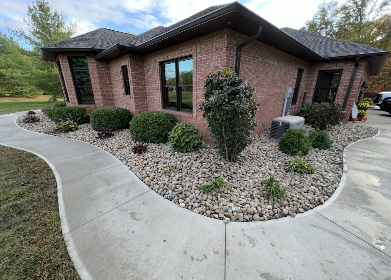 Brick home with a curved concrete walkway and rock landscaping.