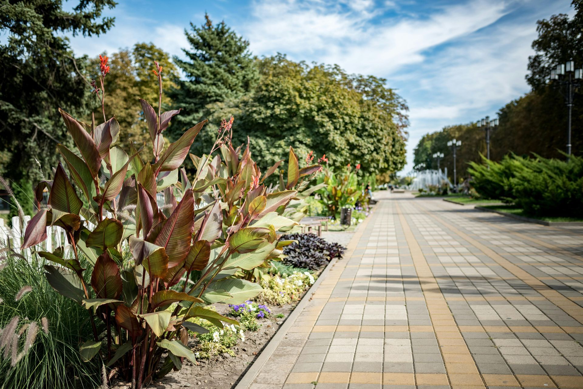 A two-story brick house with a shingled roof, surrounded by a manicured lawn and trees under a clear blue sky.