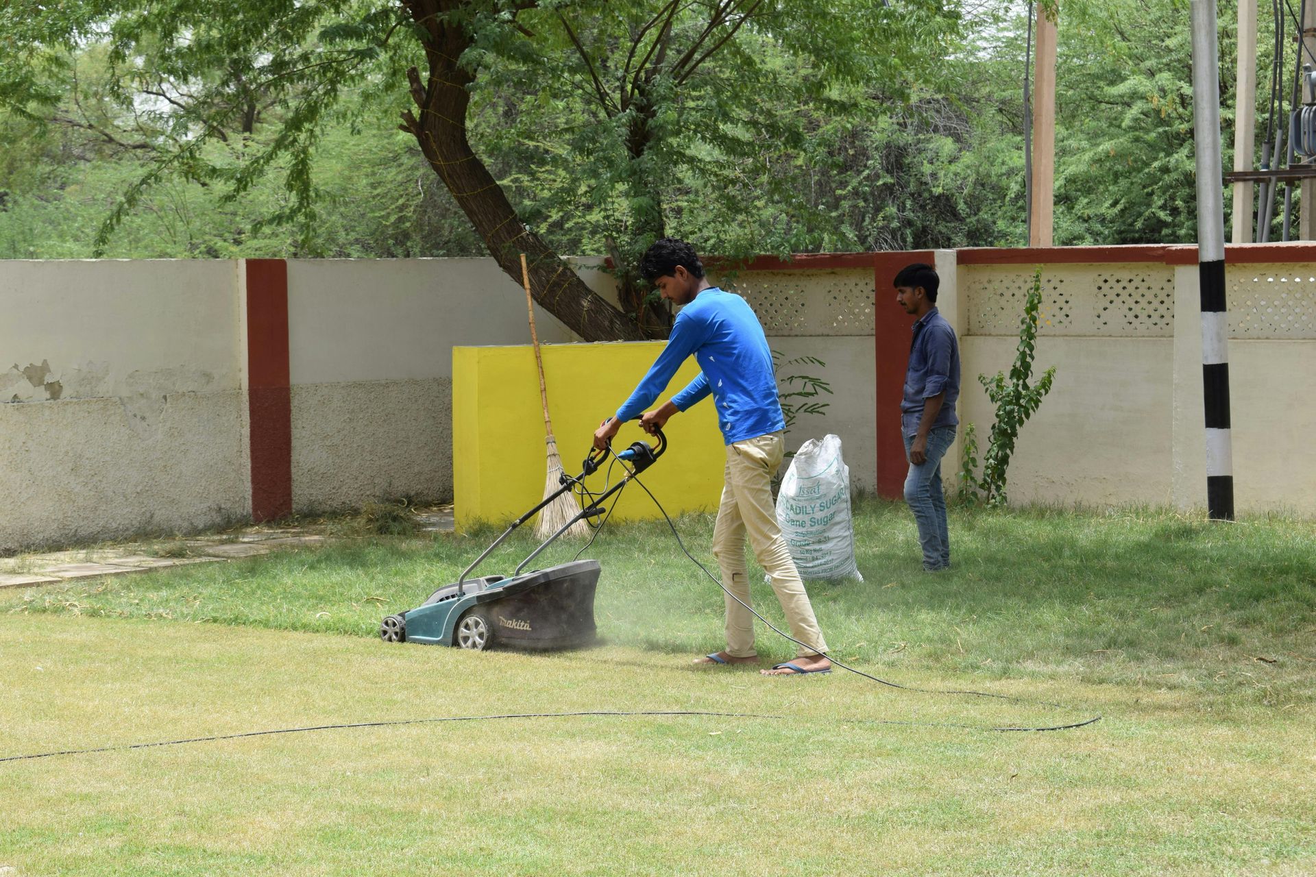 A two-story brick house with a shingled roof, surrounded by a manicured lawn and trees under a clear blue sky.