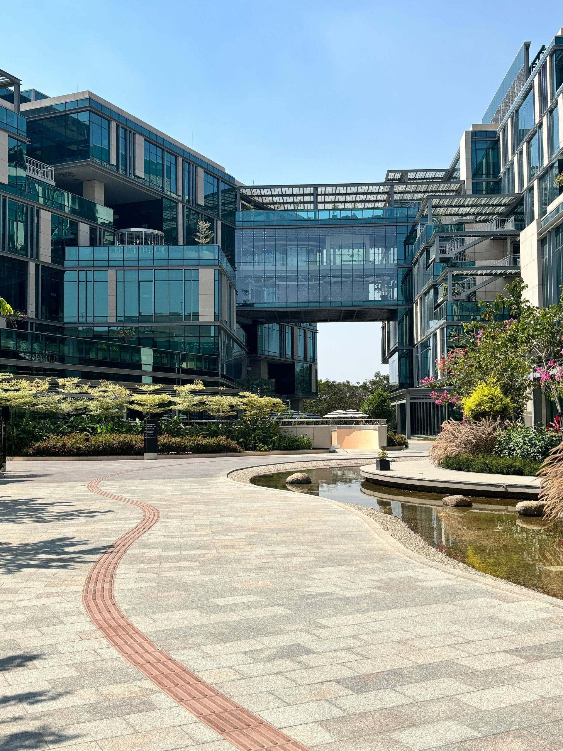 A two-story brick house with a shingled roof, surrounded by a manicured lawn and trees under a clear blue sky.