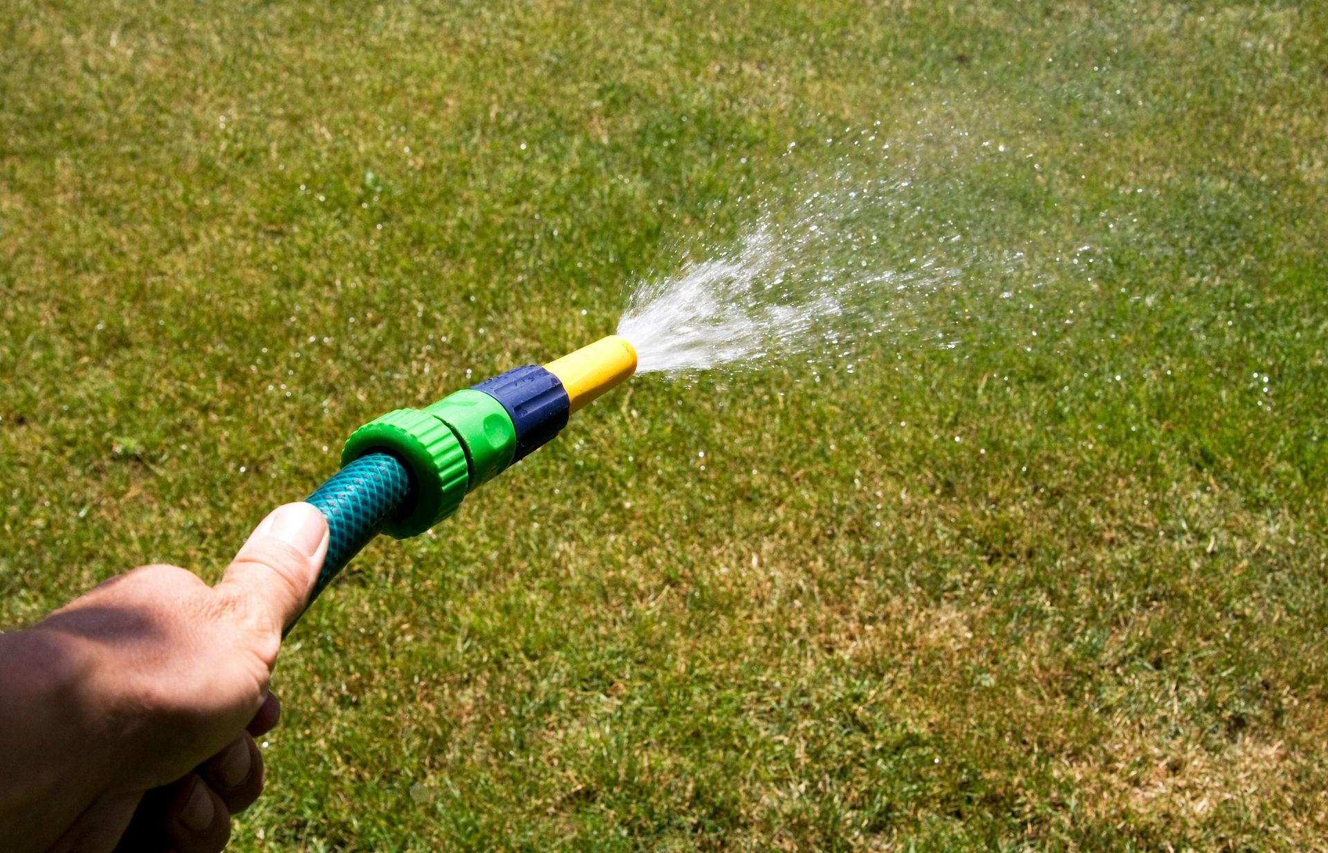 A two-story brick house with a shingled roof, surrounded by a manicured lawn and trees under a clear blue sky.