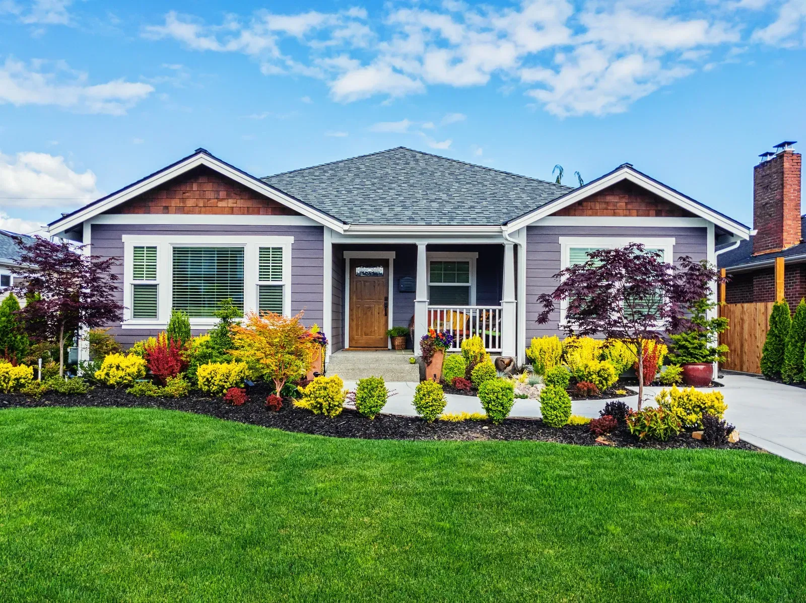 House with purple siding and landscaped front yard on a sunny day.