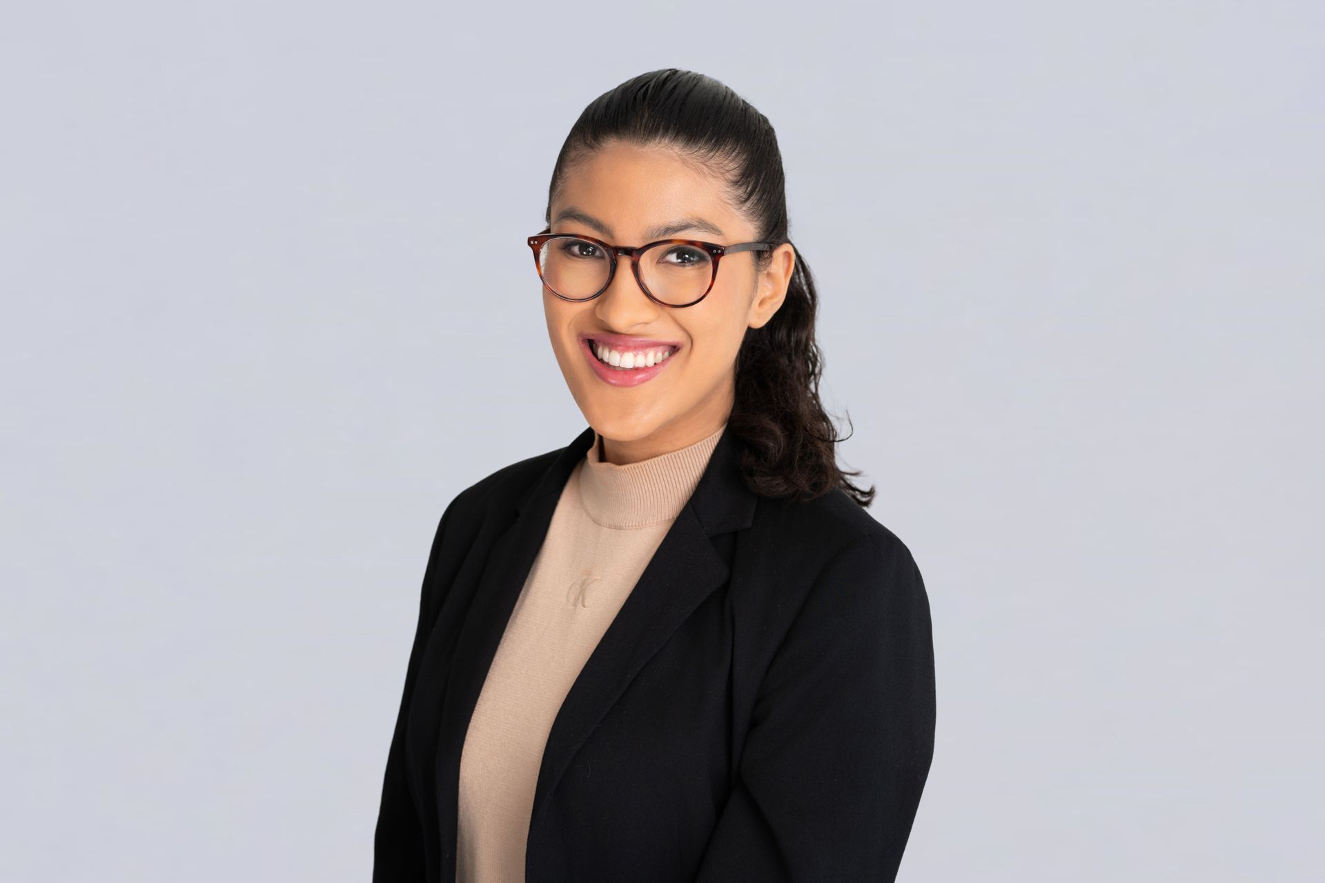 A woman in a black jacket and purple shirt is smiling for the camera.