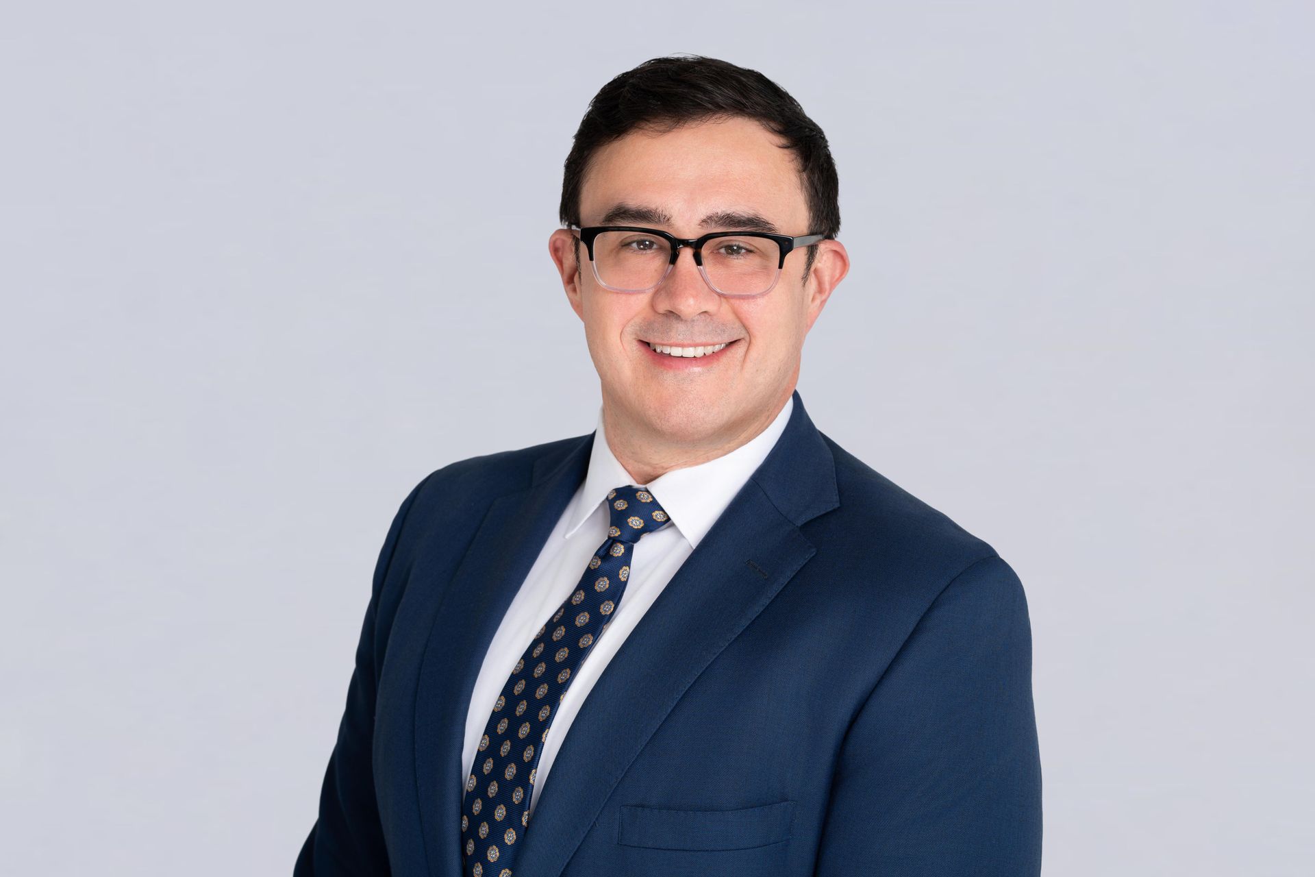 A man in a suit and tie is wearing glasses.