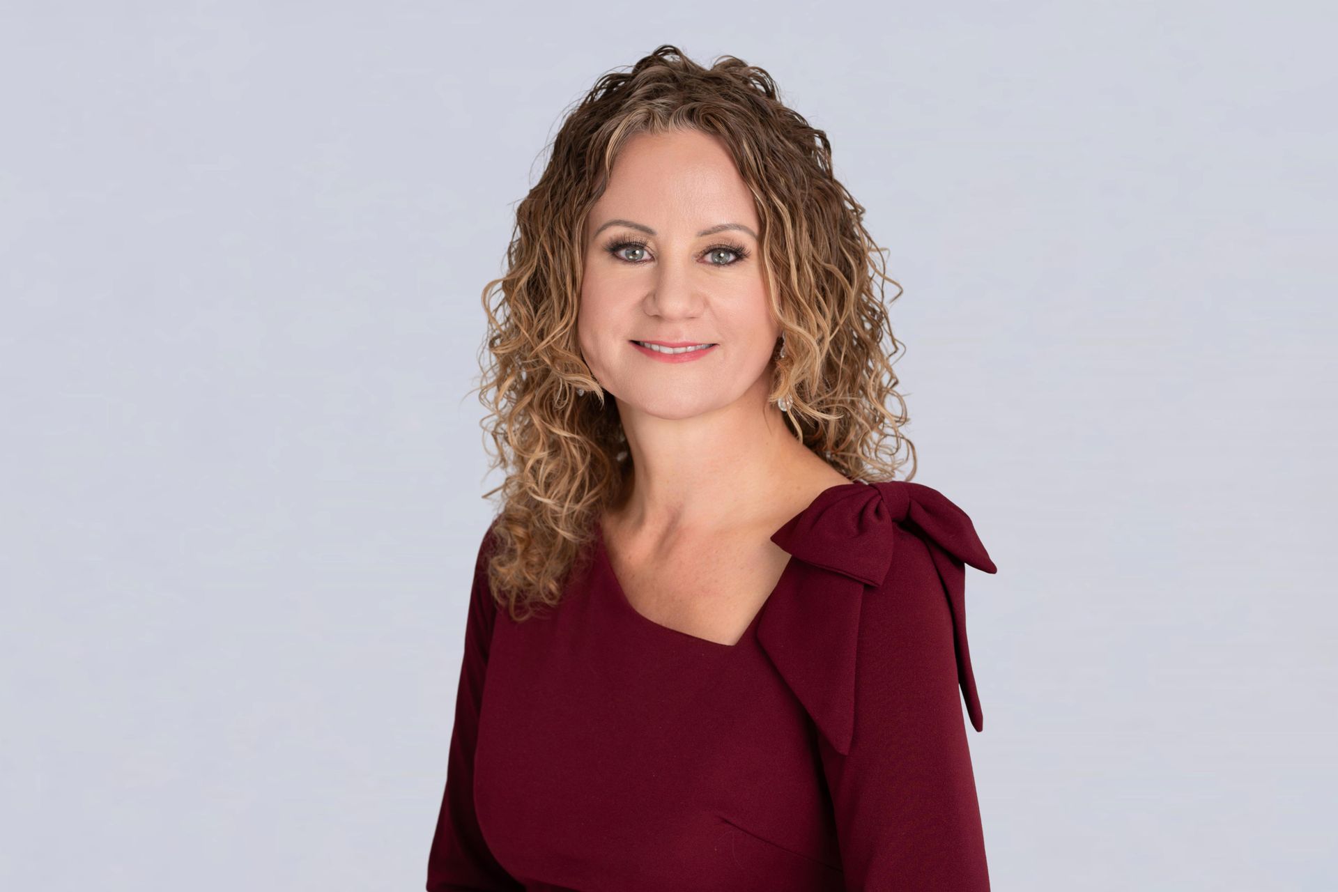A woman in a black jacket and purple shirt is smiling for the camera.