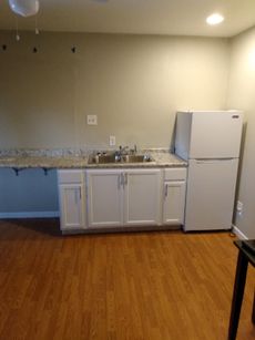 A kitchen with white cabinets a sink and a refrigerator