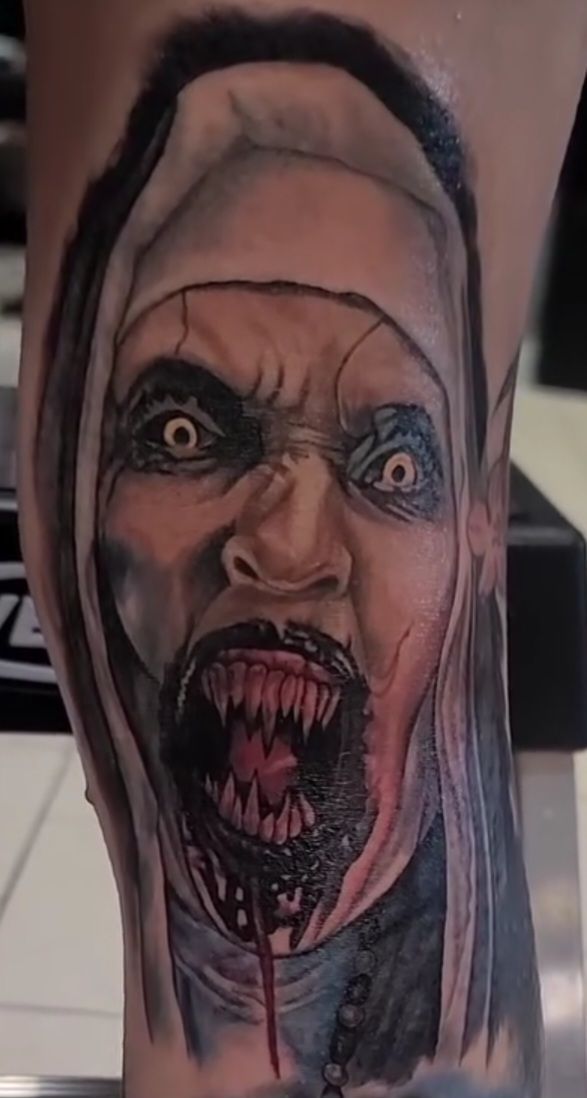 Tattoo of a scary nun with sharp teeth, blood, and a menacing expression.