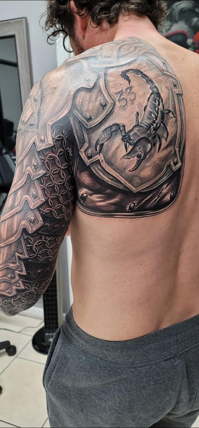 A man with a tattoo on his back is standing in a room.