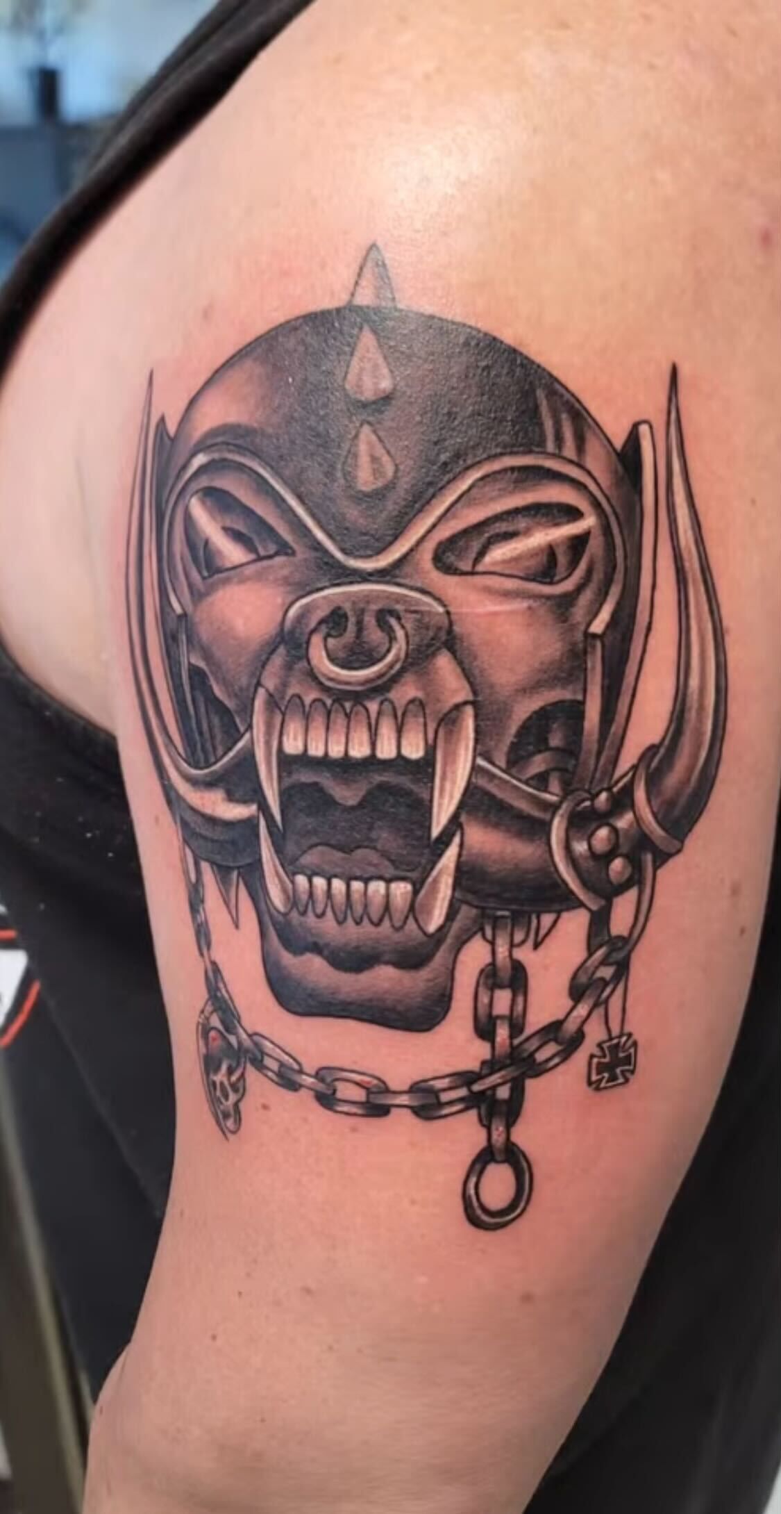 A person has a tattoo of a skull with horns on their arm.