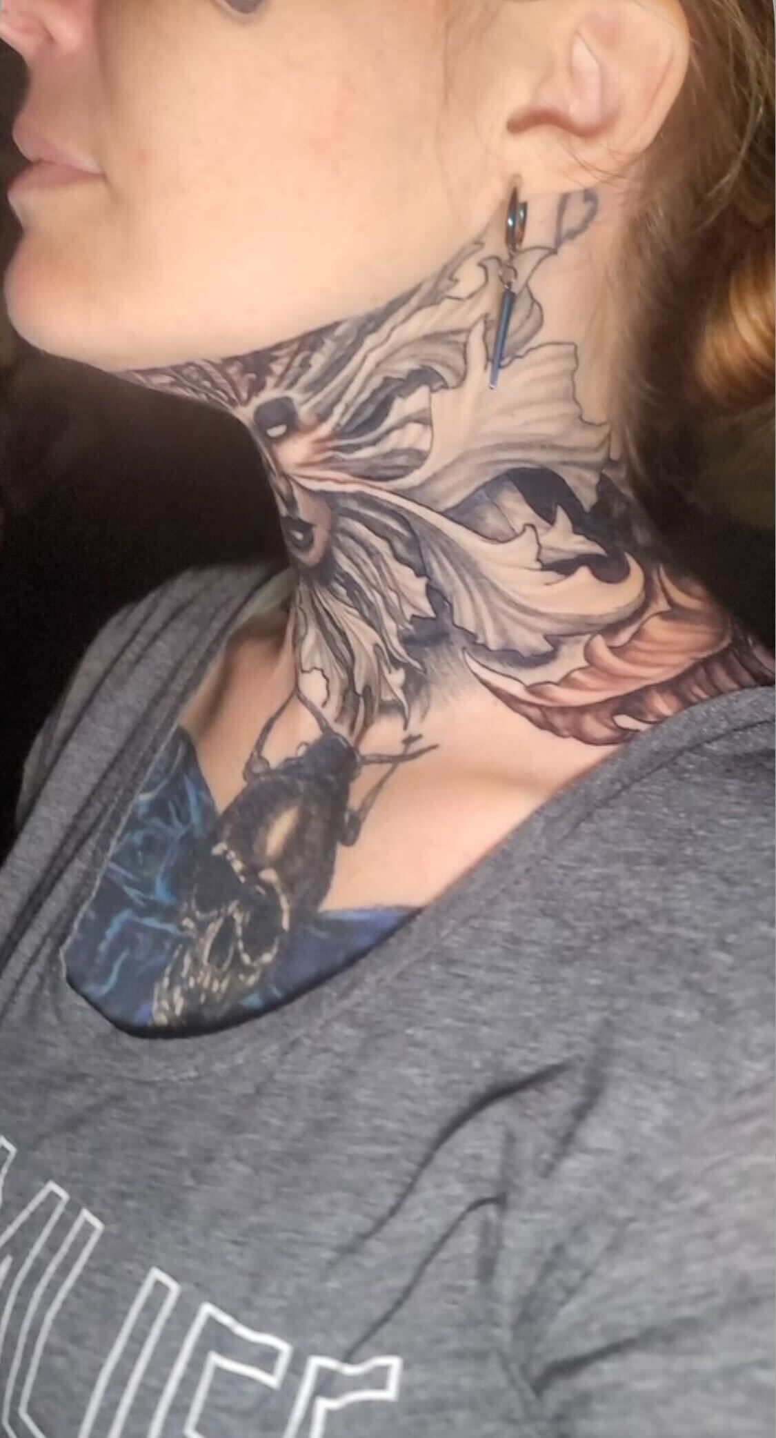 A woman has a tattoo on her neck and chest.