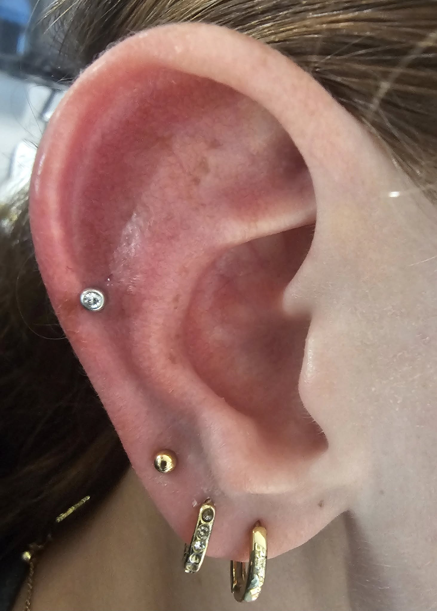 A close up of a woman 's ear with multiple piercings.