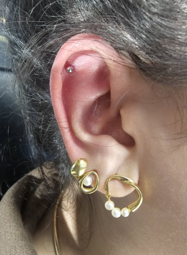 A close up of a woman 's ear with multiple piercings and earrings.