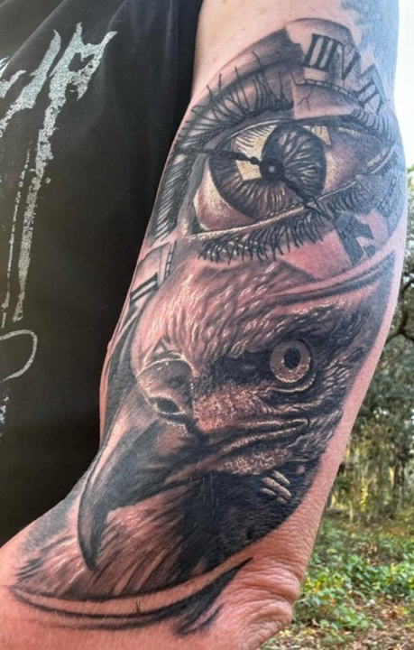 A man has a tattoo of an eagle and an eye on his arm.