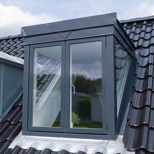 A rectangular roof window on a black tiled roof