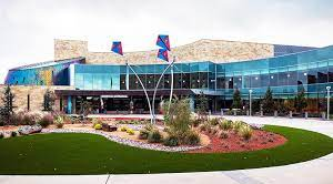 Modern building with glass facade and stone accents, landscaping in front.