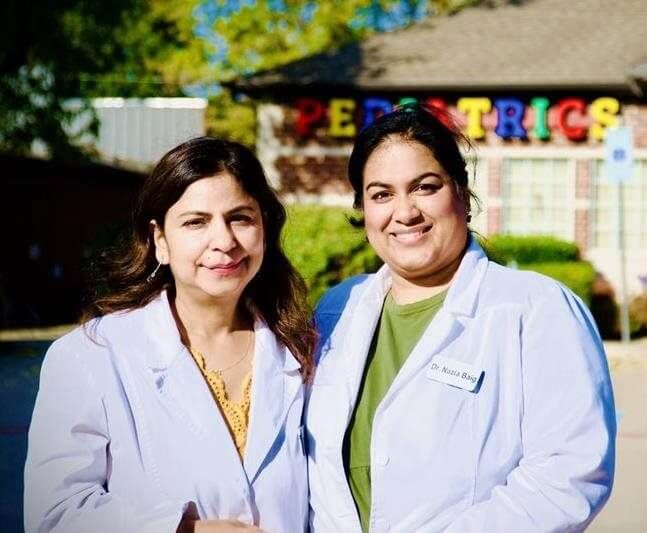 Two women in white coats outside a building with 