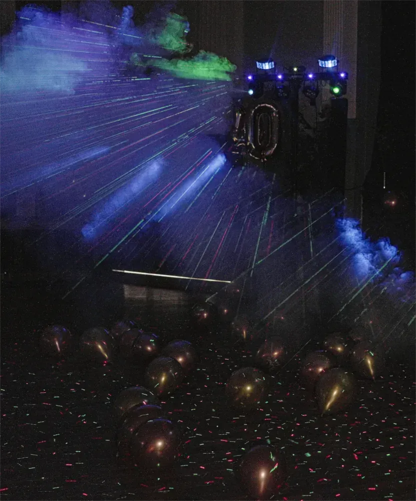 Laserlichter erhellen einen dunklen Raum voller Ballons.