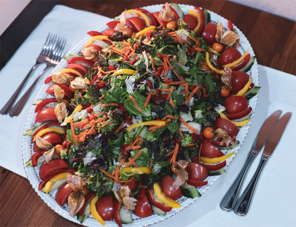 Ovale Platte mit buntem Salat aus Gemüse und Tomaten.