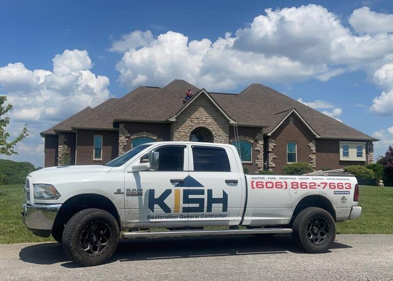 A white truck is parked in front of a large brick house.