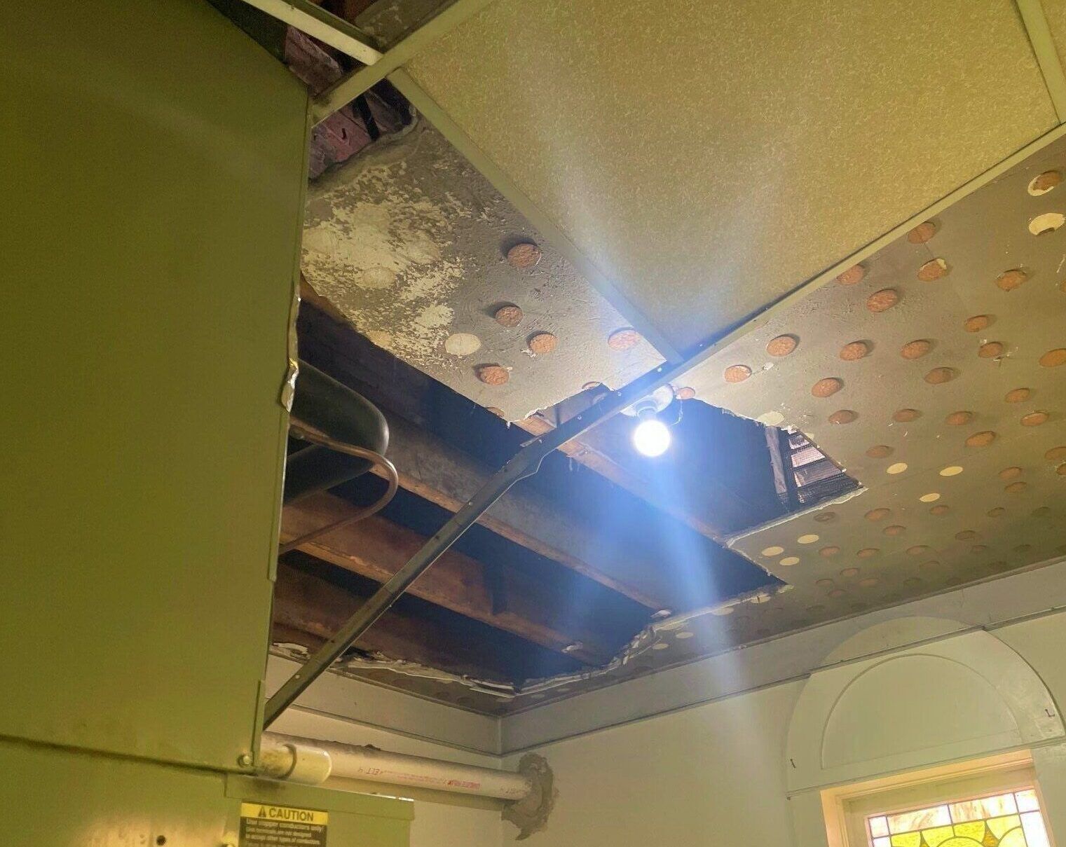 A light is shining through a hole in the ceiling of a room.