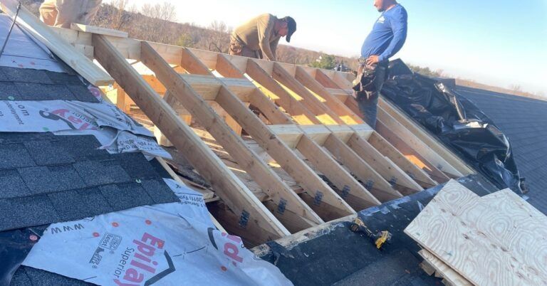 Two men are working on the roof of a house.