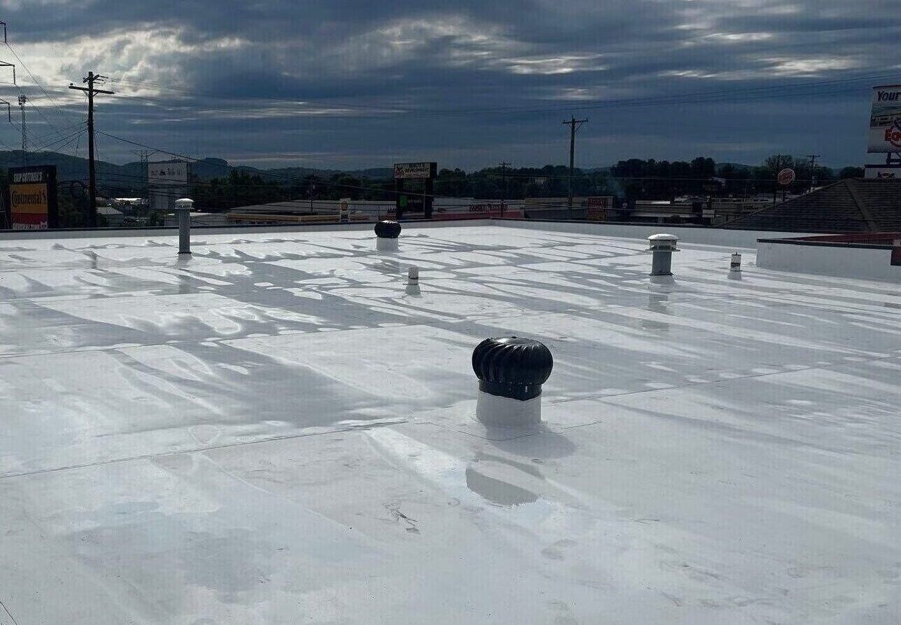 A white roof with a black vent on top of it.