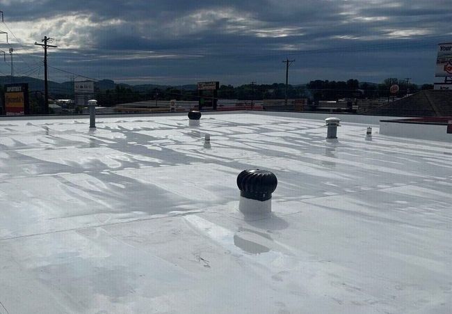 A white roof with a black vent on top of it.