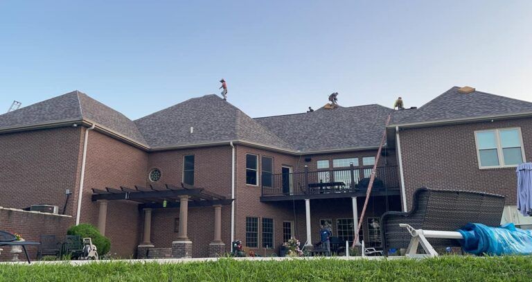 A large brick house with a roof that is being repaired.