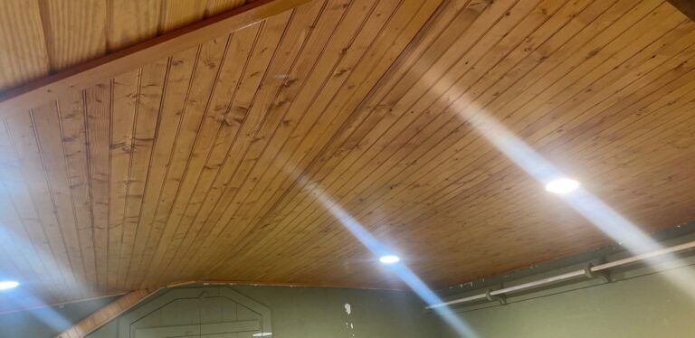 A wooden ceiling with lights shining through it in a room.