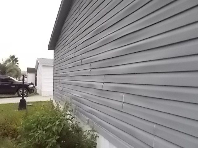 A gray house with a black truck parked in front of it.