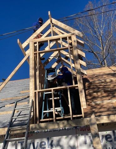 Two men are working on a wooden structure on top of a roof.
