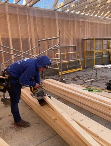 A man in a blue hoodie is cutting wood with a circular saw