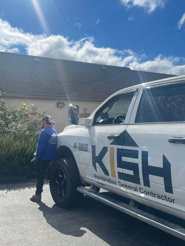 A white truck with the word kash on the side is parked in front of a building.