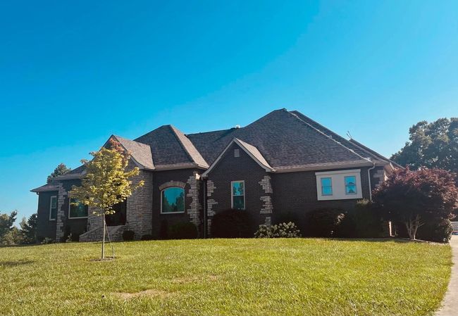 A large house is sitting on top of a lush green hill.