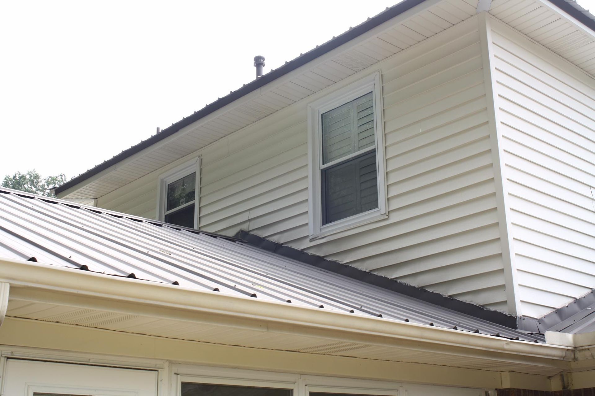 A white house with a metal roof and two windows