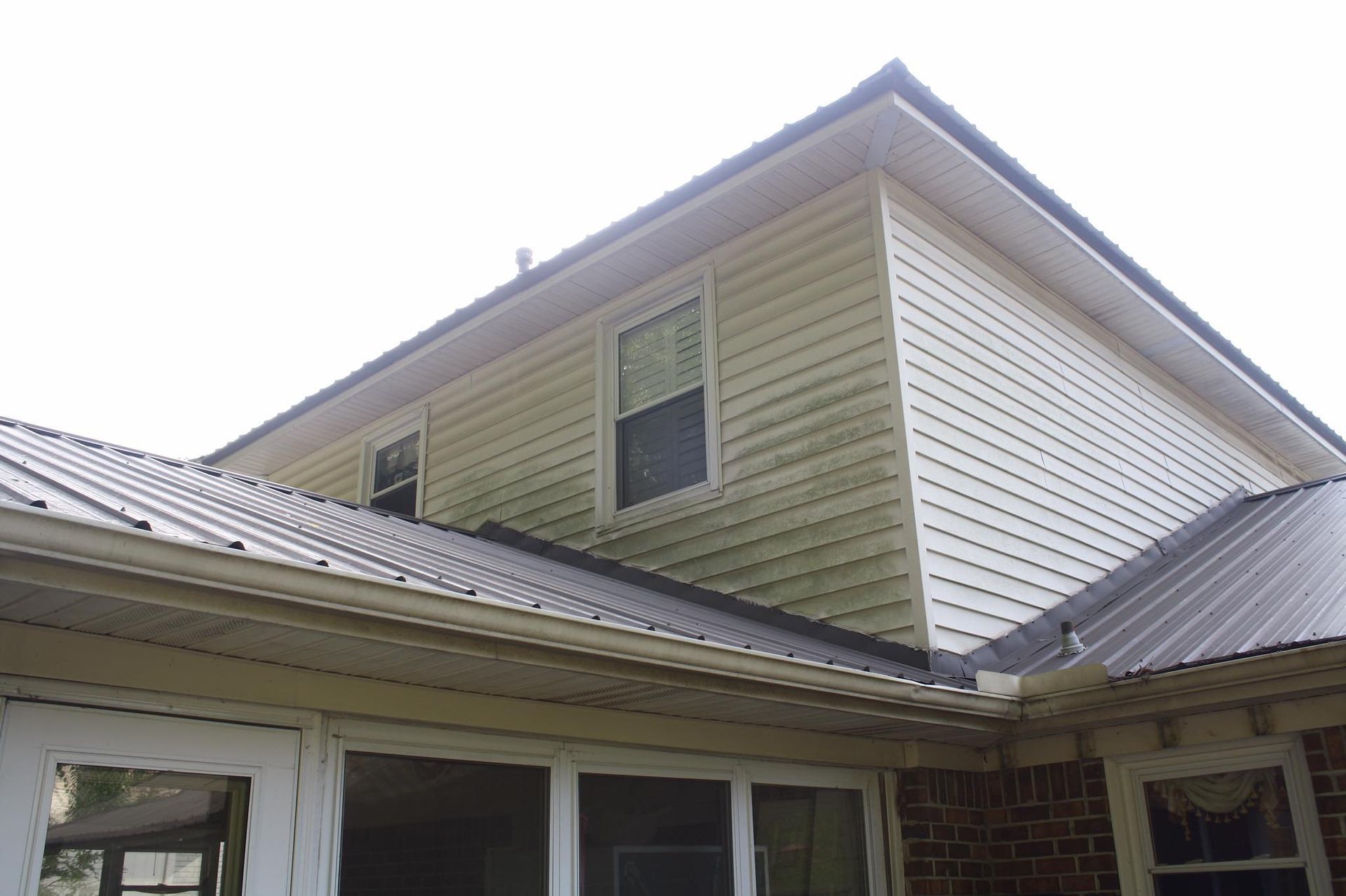 The roof of a house with a metal roof and white siding.