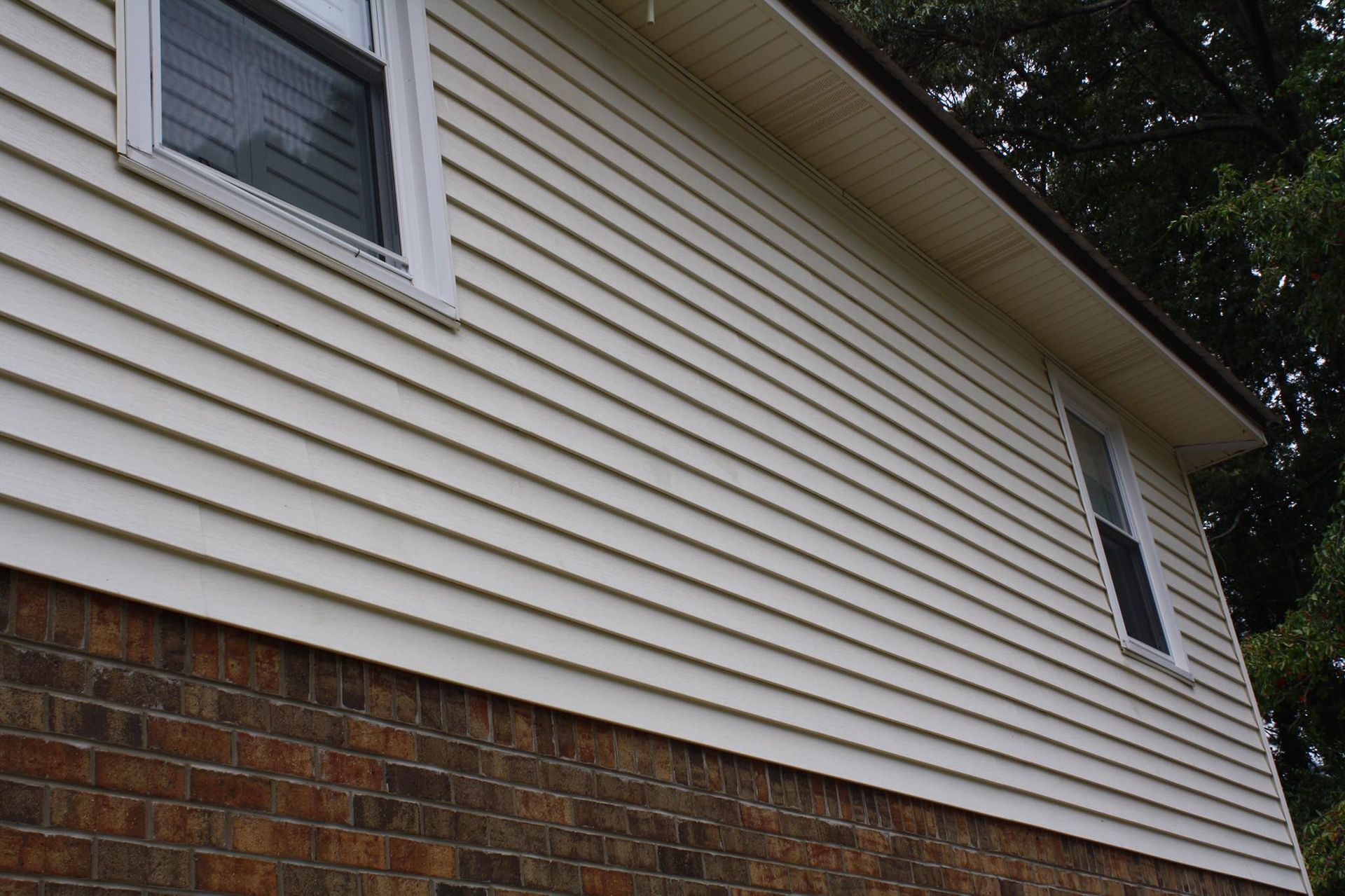 The side of a house with a white siding and two windows.