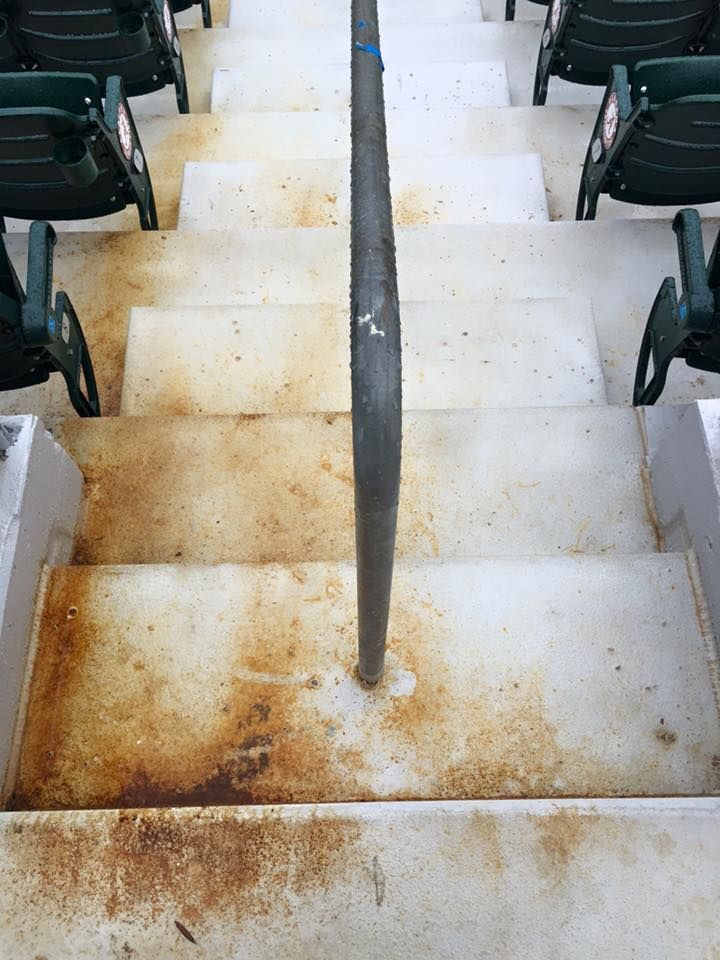 A row of stairs leading up to a stadium with a rusty railing.