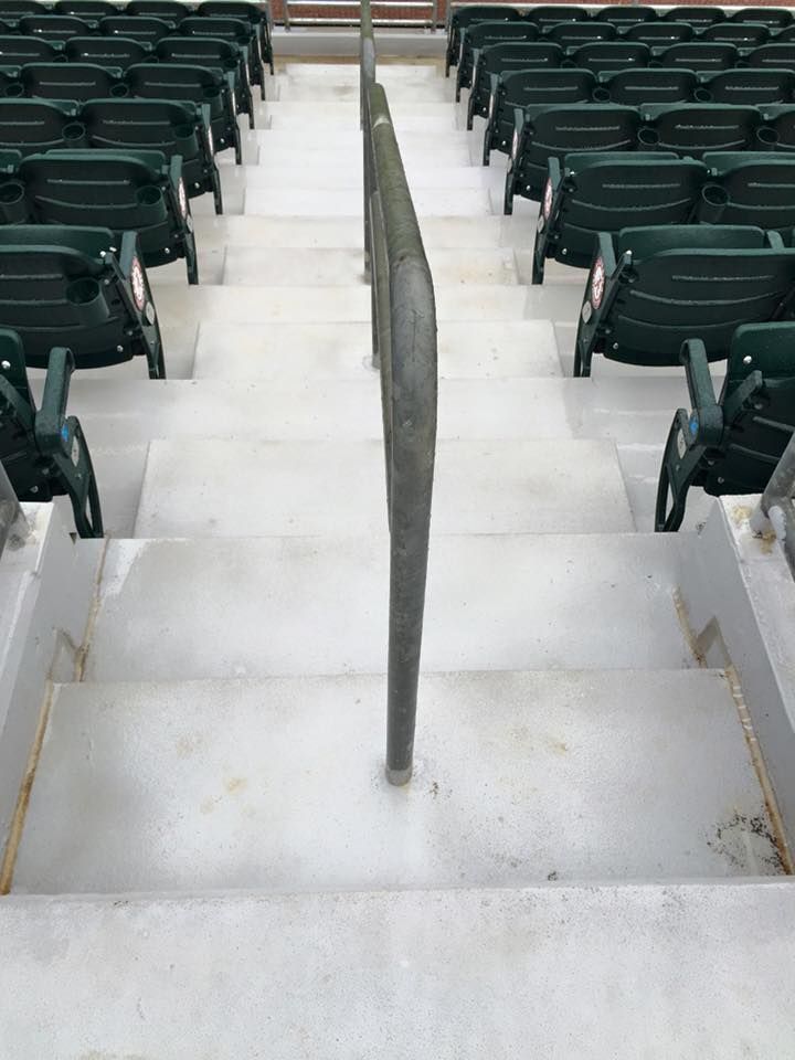 A row of bleachers with green seats and stairs leading up to them.