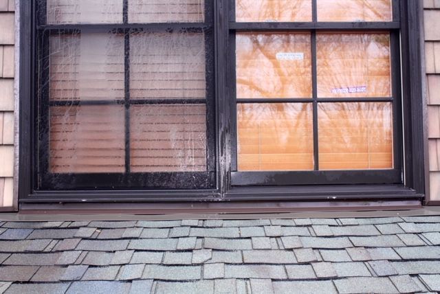 A window on the side of a house with a slate roof.