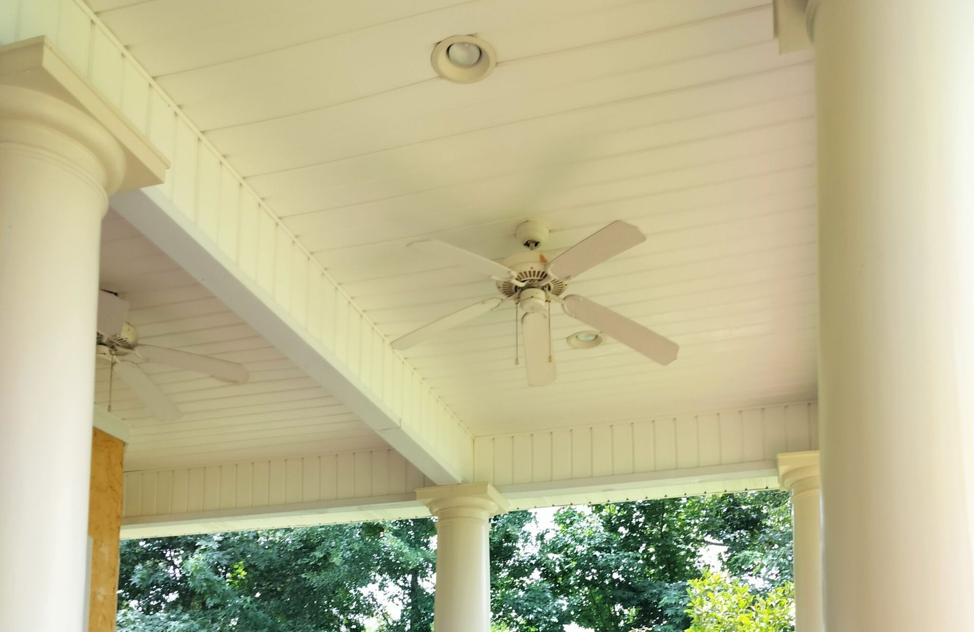 A ceiling fan is hanging from the ceiling of a porch