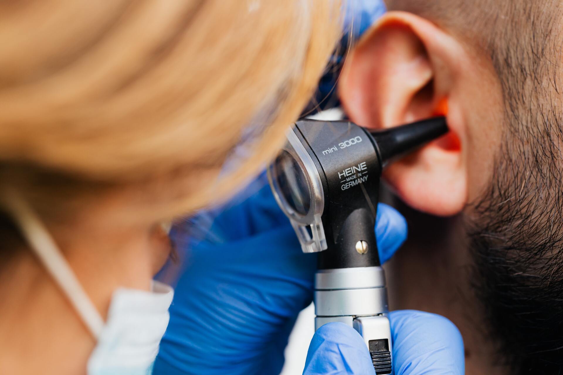 A woman is examining a man 's ear with an otoscope.