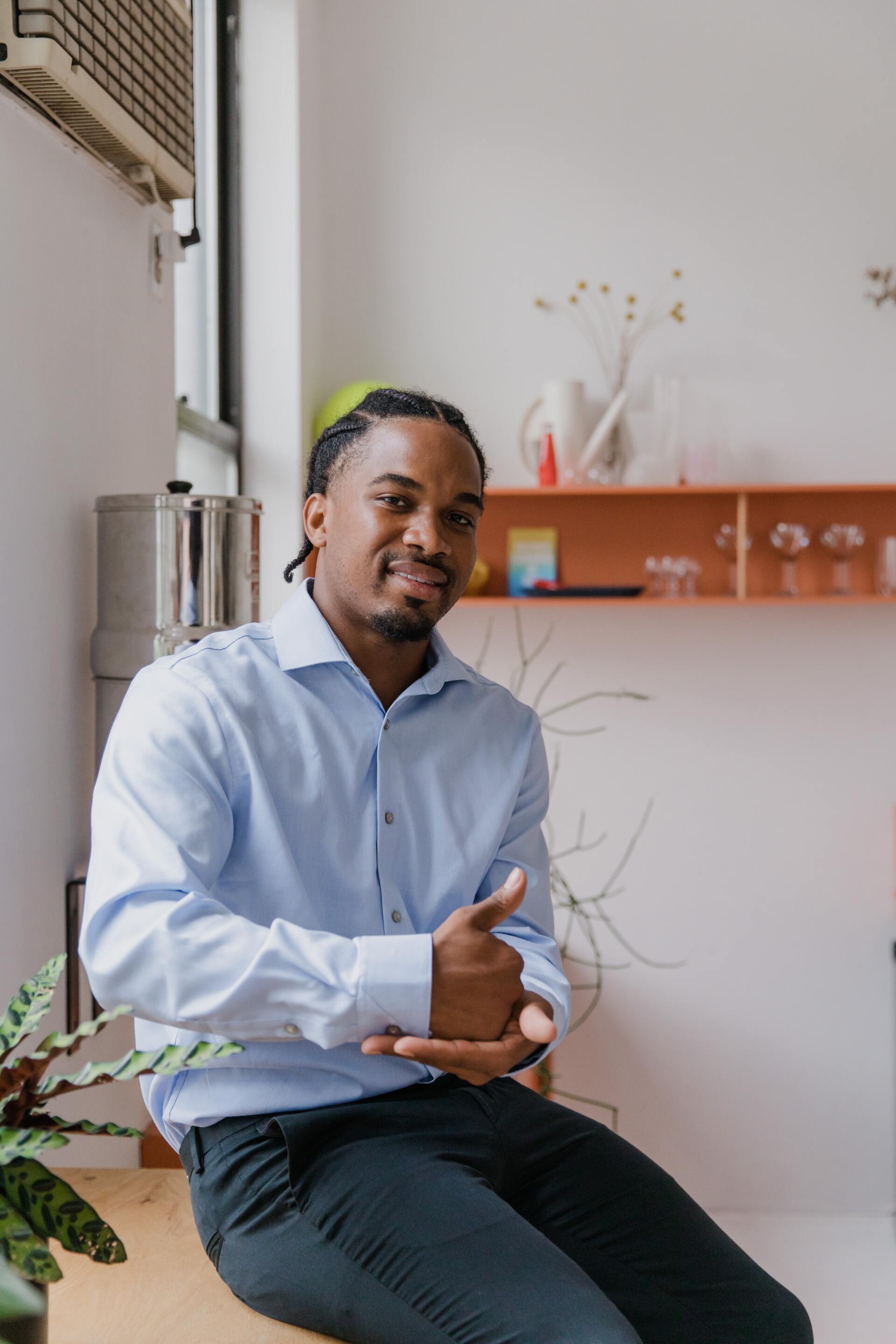 A man in a blue shirt is sitting on a table with his hands folded.