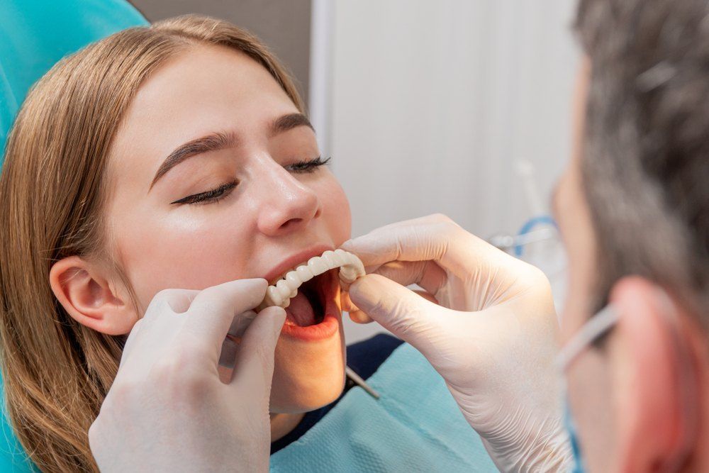 A Woman is Getting Her Teeth Examined by a Dentist — Complete Denture Clinic in Gosford, NSW