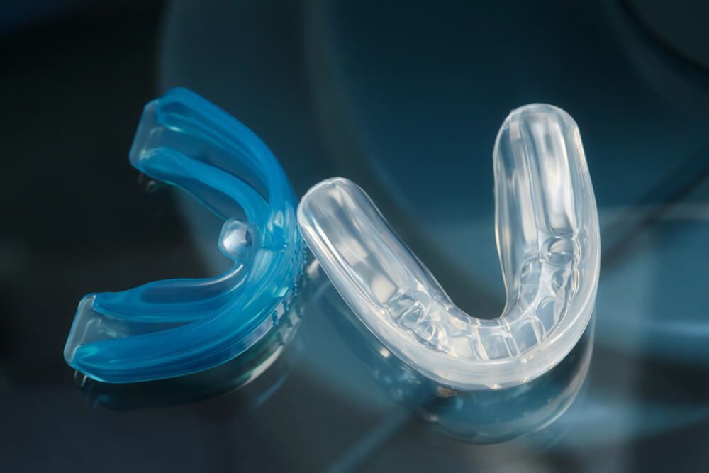 Two mouth guards are sitting on a glass table — Complete Denture Clinic in Kanwal, NSW