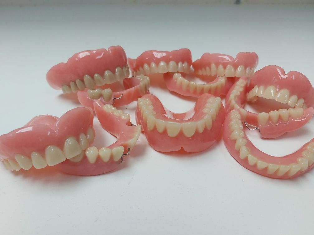 A Bunch of Dentures Are Sitting on a White Surface — Complete Denture Clinic in Kanwal, NSW